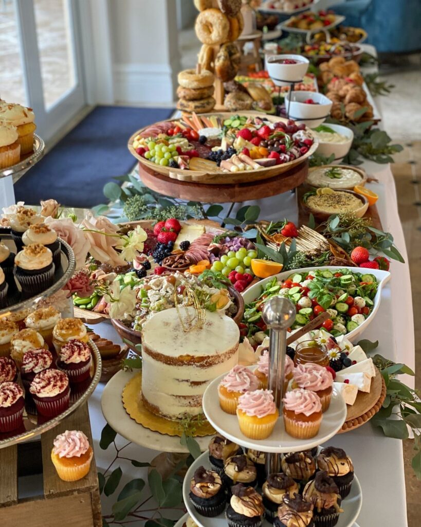 Lavish brunch spread with a naked cake, cupcakes, and charcuterie on a table.