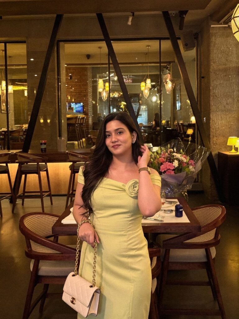 Woman in a light yellow summer dress holding a white handbag in a restaurant