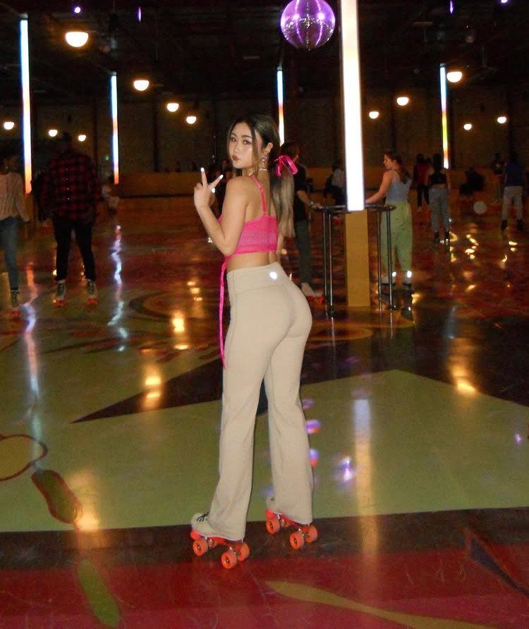 Woman in roller skates posing inside a colorful roller rink with a disco ball.