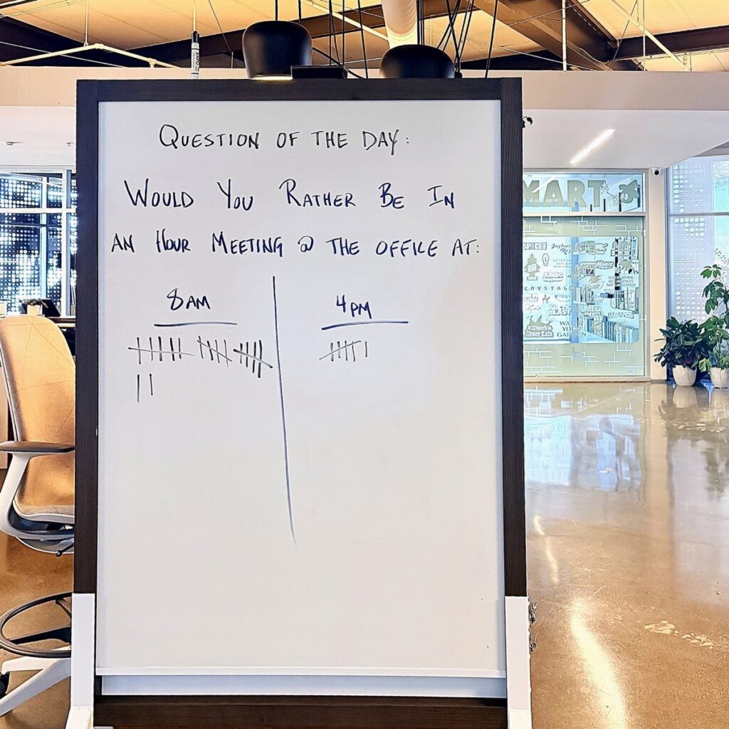 Whiteboard in an office with a 'Would You Rather' question and tally marks.