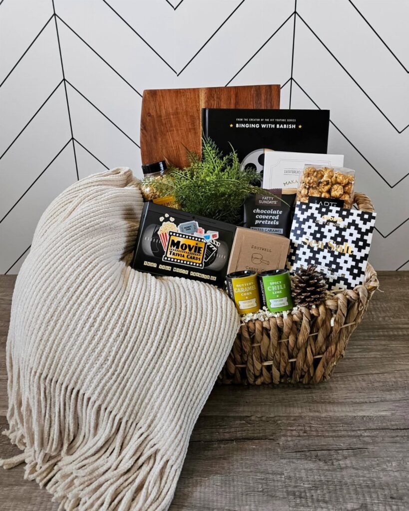 Woven gift basket with movie snacks, a blanket, and a movie ticket box.