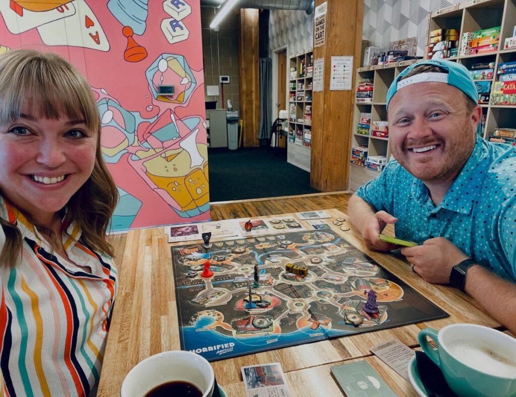 A couple smiling while playing a board game at a board game cafe.