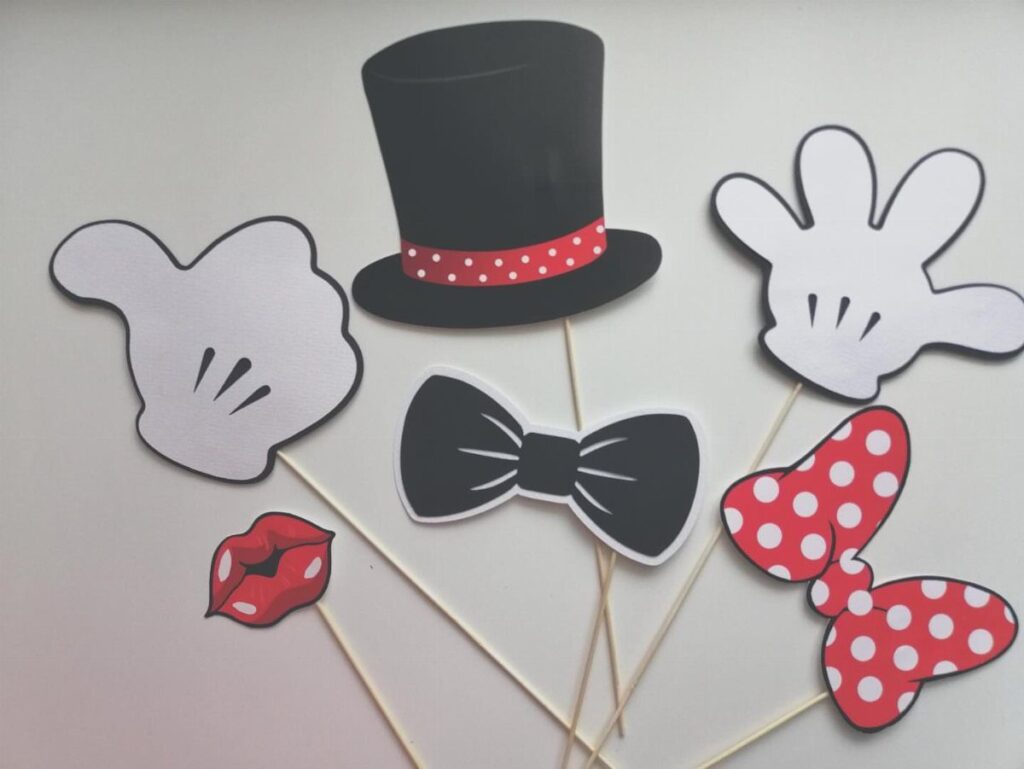 Paper photo booth props including a top hat, gloves, and red polka dot bow.