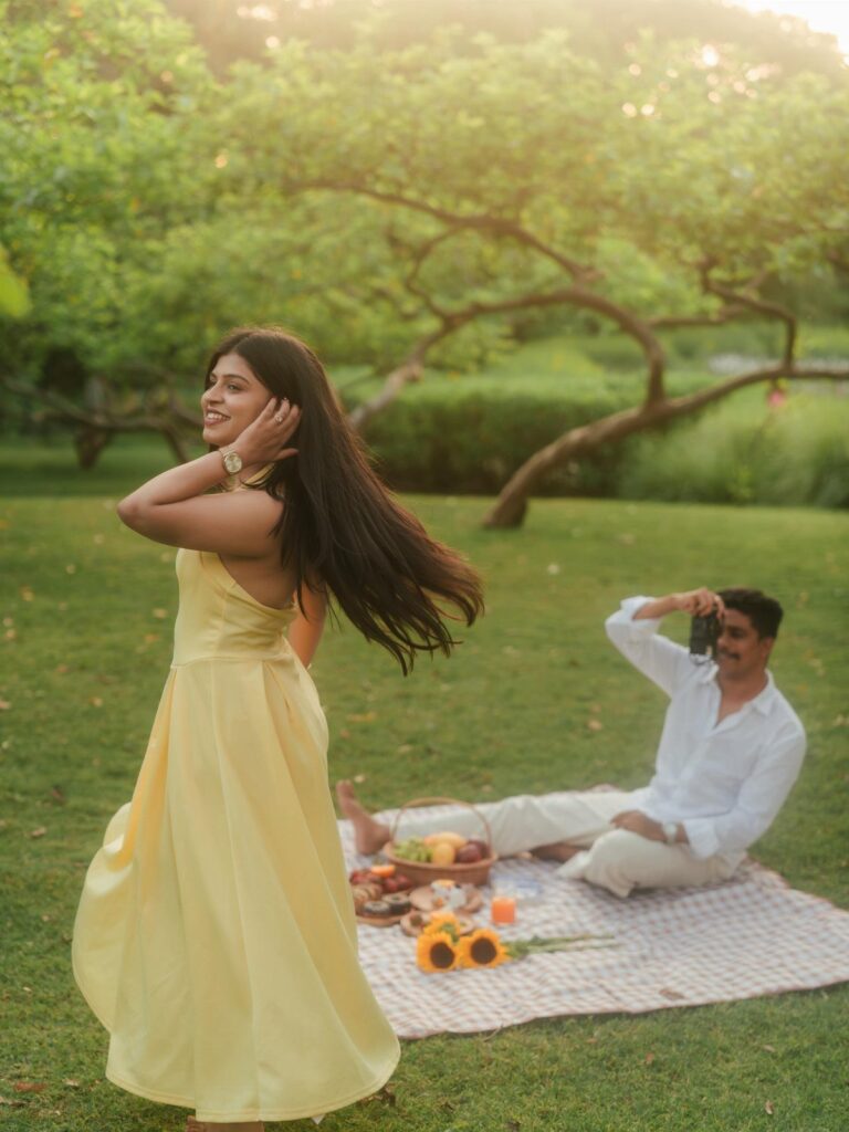 Couple enjoying a picnic with a basket and snacks in a sunny park.