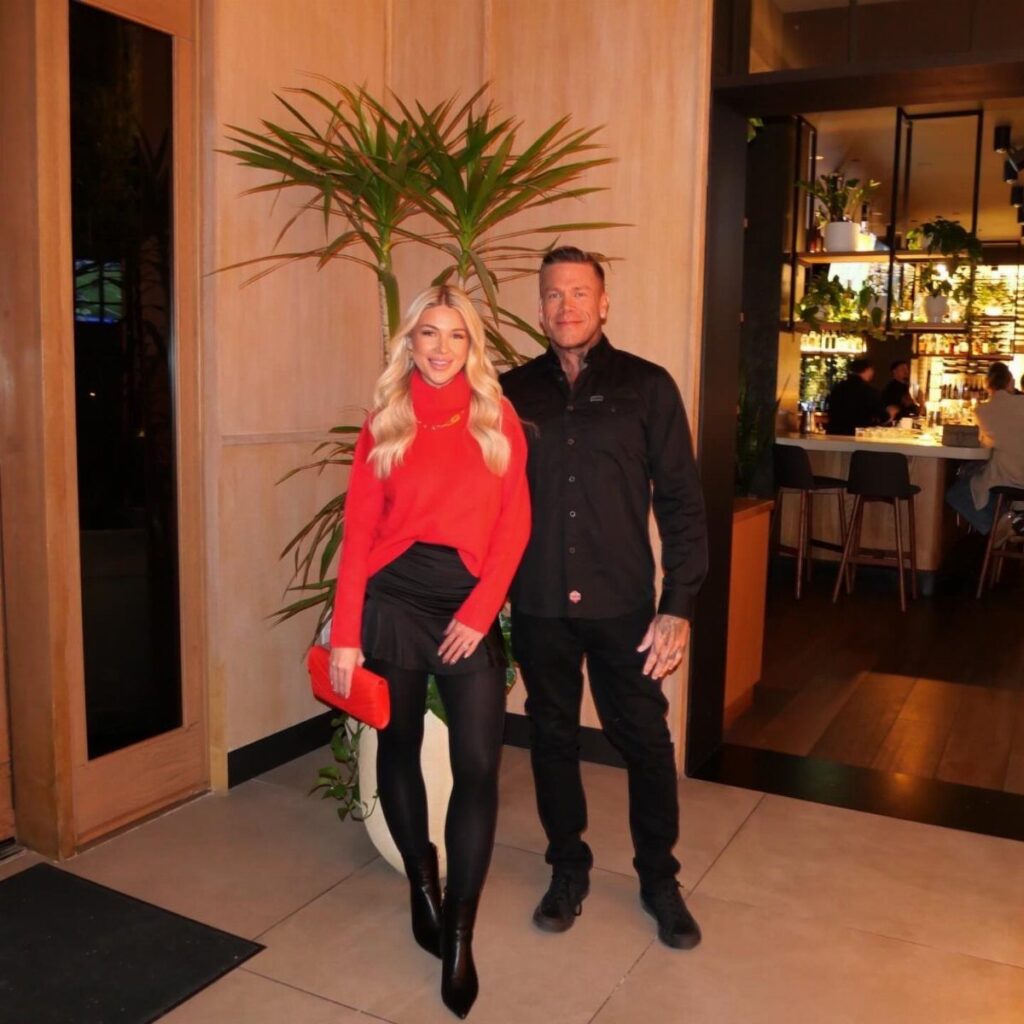Man and woman posing in stylish black and red winter evening attire outdoors.